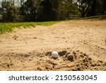 Small photo of Selective focus of white golf ball on the green field and sand bunker with sunlight. Golf ball on the sand in beautiful golf course at sunset background.