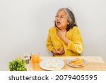 Small photo of Senior asian women have acid reflux problems. While eating patty, food stuck in the throat, esophageal burning sensation, irritation, coughing, suffocation and difficulty swallowing.