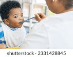 Small photo of Mother raising take care an African-American Thai son feeds him simple and nutritious lunch : Portrait baby boy who enjoys eating food relishing and gluttonous.