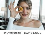 Close up fun emotional young female is holding bitcoin in front eye. Online virtual future currency concept. Beauty woman head with Bitcoin money in eye. Digital cryptocurrency bitcoin.