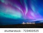 colorful northern lights in a iceland landscape with cottage mountain and sea