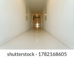 Small photo of Long narrow deadened walkway in condominium with many close doors and exit sign. High-rise living property, real estate market concept.