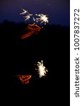 Small photo of happy holidays.Vintage flim grain Style. Abstract blur background,woman hand holding a burning sparkler light with purple sky background.closeup in female hand in dark.