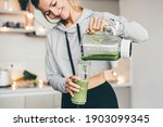 Woman Making Detox Smoothie At Home. Woman pouring smoothie to glass. healthy food concept
