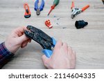 Small photo of A male electrician changes the plug on an electric wire. Working with electrical tools. Stripper, crimp, screwdriver, wire cutters.