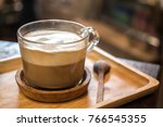 A cup of capuccino latte art coffee and spoon on wooden table background.