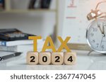 Tax and Vat 2024 Concept.Tax wooden letters on wooden cubes with 2024 on coins. income tax online return form for payment. Expenses, account, VAT, pay tax in 2024 year.