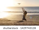 Using a drone uses remote control on the beach. Full length shot of young woman operating the drone by remote control at the sea shore. Brazil.