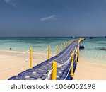 Small photo of Blue plastic bridge with yellow rail is the way through the sea.