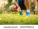 athlete man tying running shoes lace in the park outdoor, sportman ready for jogging on the road outside, asian Fitness walking and exercise on green grass in morning. wellness and sport concepts