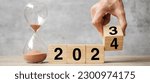 Small photo of hand flipping block 2023 to 2024 text with hourglass on table. Resolution, time, plan, goal, motivation, reboot, countdown and New Year holiday concepts