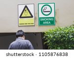 Small photo of A man is walking his smoking. The smoking area under the building. And there are warning signs of head hit the ceiling.