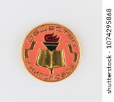 Small photo of OMSK, RUSSIA, April 22, 2018: an icon made in the USSR shows an image of a gilded book and a torch and an inscription "The Society of Booklovers," close-up on a gray background