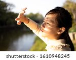 Asian child girl covering face by hand to protect,prevent face skin from bright sun in outdoor summer,female people hand covered the strong sun light feeling hot uncomfortable,risk of eyes damage 