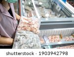 Small photo of Asian woman choosing frozen food products,compare the dissimilarity between fresh shrimp and frozen raw shrimp,buy the necessary food,hoard packed frozen seafood at freezer,shopping in the supermarket