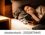 Small photo of Drowsy woman lying in bed,addicted to her phone,constantly yawning,feeling tired,her heavy eyelids struggling to stay open,battled her sleepy state,symptoms of sleep procrastination or revenge bedtime