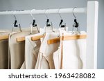 Many paper sewing patterns for different clothes hanging on the rack in sewing factory background. Clothing pattern, manufacture on sewing factory. Tailoring, small business