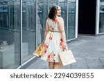 How to Shop for Summer Fashion on a Budget. Choosing the Right Fabrics for Hot and Humid Summer Weather. Outdoor portrait of stylish curvy woman with shopping bags