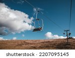 Ski chair-lift in front of the blue sky on a sunny day. No people. Elevator in the autumn season