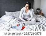 hispanic woman lying on bed and working with her laptop in home office concept in Mexico Latin America