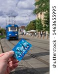 Small photo of Moscow/Russia; July 3 2019: Moscow Troika transport card on left hand, with blue electric tram background