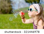 a little girl making soap bubbles in nature