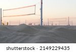 Small photo of Players playing volleyball on beach court, volley ball game with ball and net, sunset palm trees silhouette, California coast, USA. Defocused people on sandy ocean shore. Seamless looped cinemagraph.
