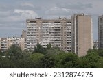 Facade of an overcrowded shabby apartment buildings of a multi-storey Soviet panel house, on a hot summer day.