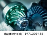 Small photo of Artistic detail of steel gear wheels inside angle grinder machine in green blue shade. Mechanism of power tool engine with locking nut and ball bearing on cogwheel with pinion. Metallic cogged parts.