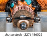 Small photo of Closeup of commutator copper segments and plain bearing bronze housing in plastic pillow block. Steel flat leaf spring with screws inside old blender electric motor with rotor and stator wire winding.