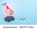 Small photo of Mock up human heart, pills and syringe on a blue background. Concept of heart disease treatment with medication, pharmacotherapy, copy space for text, stenocardia