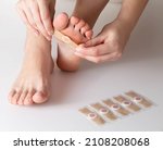 Small photo of Woman sticks a medical plaster to the plantar wart of the leg to remove dead skin and calluses, close-up