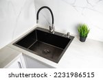 Small photo of Modern kitchen sink with detergent dispenser and faucet with curved movable hose. Kitchen faucet with curved spout against white porcelain tiles