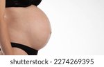 Small photo of Body of a pregnant woman in black underwear on a white background. Fetal period, hormonal changes in a pregnant girl.