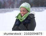 Small photo of Portrait of frozen suffering girl, young black African Afro American freezing woman standing walking outdoors at winter snowy cold frosty day, shaking, trembling, shivering in jacket, hat, scarf