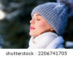 Side beauty portrait of beautiful attractive girl, young calm woman is breathing deep deeply fresh air at winter cold frosty snowy day with her eyes closed, meditating, doing breath exercise, enjoying