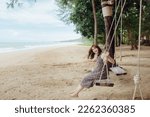 Asian beautiful woman sitting on wooden swing at the seaside