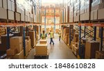 Small photo of Retail Warehouse full of Shelves with Goods in Cardboard Boxes, Workers Scan and Sort Packages, Move Inventory with Pallet Trucks and Forklifts. Product Distribution Logistics Center. Elevated Shot