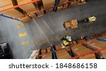 Top-Down View: Worker Moves Cardboard Boxes using Hand Pallet Truck, Walking between Rows of Shelves with Goods in Retail Warehouse. People Work in Product Distribution Logistics Center