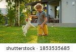 Small photo of Cute Boy Plays with His Favourite Dog Friend while Having Picnic Outdoors on the Lawn. He Pets and Teases His Little Smooth Fox Terrier with His Favourite Toy. Idyllic Summer House.