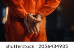 Small photo of Cinematic Close Up Footage of a Handcuffed Convict at a Law and Justice Court Trial. Handcuffs on Accused Criminal in Orange Jail Jumpsuit. Law Offender Sentenced to Serve Jail Time.