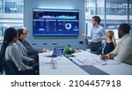 Small photo of Office Conference Room Meeting Presentation: Latin Businessman Talks, Uses Wall TV to Show Company Growth with Big Data Analysis, Graphs, Charts, Infographics. Multi-Ethnic e-Commerce Startup Workers