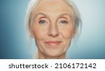 Small photo of Medium Portrait of Beautiful Senior Woman Looking at Camera and Smiling Wonderfully. Gorgeous Looking Elderly Female with Natural Beauty of Grey Hair, Blue Eyes. Abstract Blue Background
