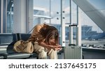 Small photo of Airport Terminal: Woman Waits for Flight, Uses Smartphone, Receives Bad News, Starts Crying. Upset, Sad, and Dissappointed Person Misses Her Flight while Sitting in a Boarding Lounge of Airline Hub.