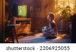 Small photo of Young Excited Sports Fan Watches a Soccer Match on TV at Home. Curious Boy Supporting His Favorite Football Team, Feeling Proud When Players Score a Goal. Nostalgic and Retro Childhood Concept.