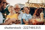 Small photo of Happy Senior Grandfather Talking and Having Fun with His Grandchildren, Holding Them on Lap at a Outdoors Dinner with Food and Drinks. Adults at a Garden Party Together with Kids.