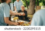 Small photo of Happy Middle Aged Man with Disabilities Using Wheelchair Receiving a Charity Meal from a Humanitarian Aid Food Bank. Volunteers Helping People in Need in Local Community.