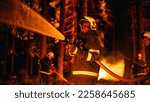 Small photo of Portrait of a Handsome African American Firefighter Methodically Extinguishing a Forest Fire with the Help of a Fire Hose. Firemen Brigade Rescuing Wildland from Uncontrollable Arson.