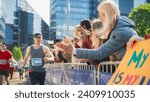 Small photo of Portrait of a Male Marathon Runner Giving a High Five to Female Family Member in the Audience While Running. Middle Aged Wife Supporting her Husband in a Charity City Marathon Race