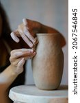 Small photo of Handicraft art: cropped image of female artisan working with wet clay decorating and shaping jug before baking in pottery studio. Craftswoman creating handmade tableware in workshop creative space.